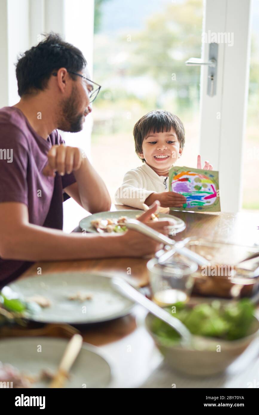 Padre e figlio mangiano e colorano a tavola Foto Stock