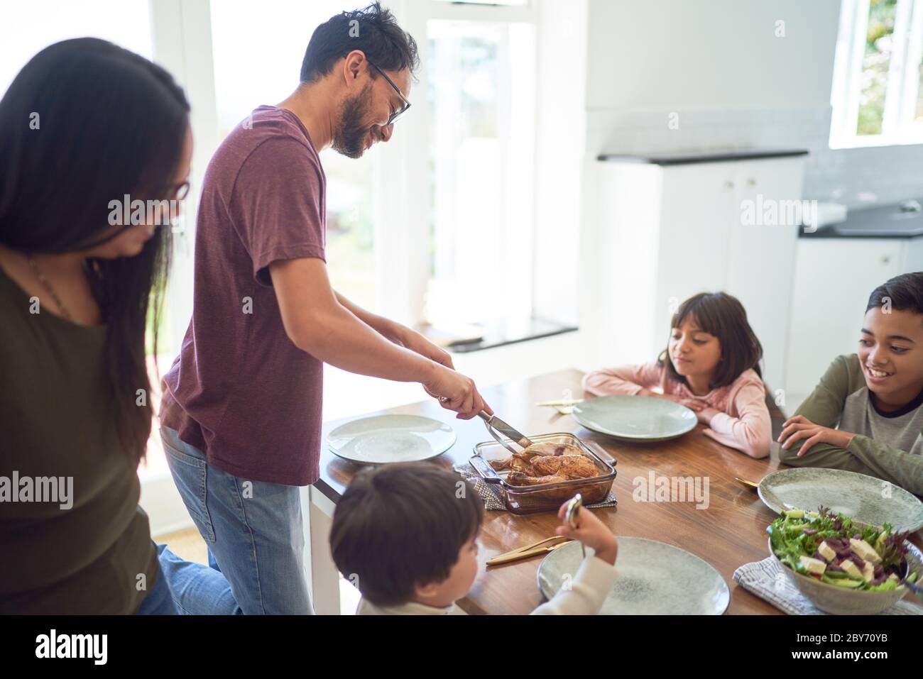 La famiglia serve e cena al tavolo da pranzo Foto Stock