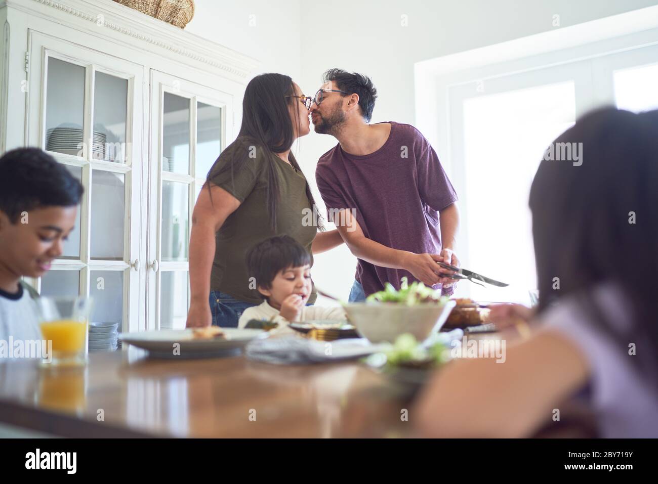 Affettuosa coppia baciando al tavolo da pranzo Foto Stock