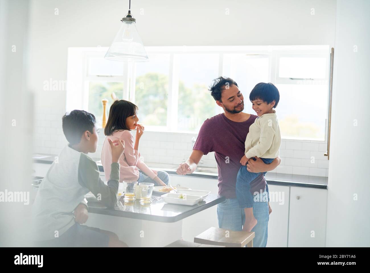 Padre e bambini che mangiano in cucina Foto Stock