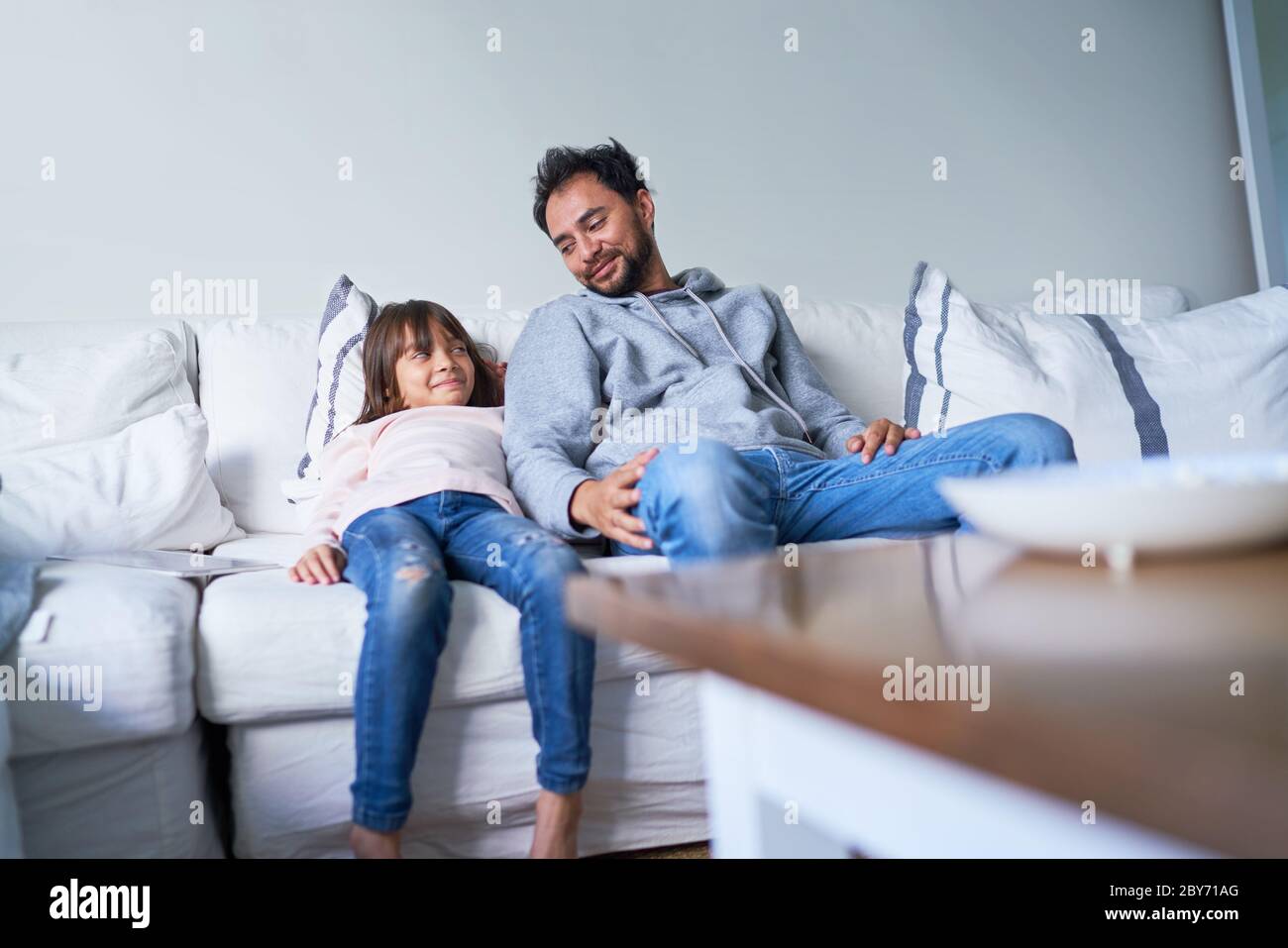 Padre e figlia si rilassano sul divano del soggiorno Foto Stock
