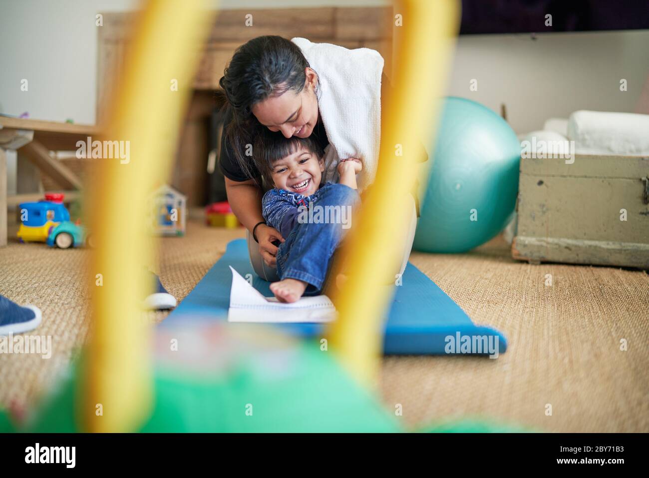 Madre felice e figlio che gioca sul tappeto yoga Foto Stock