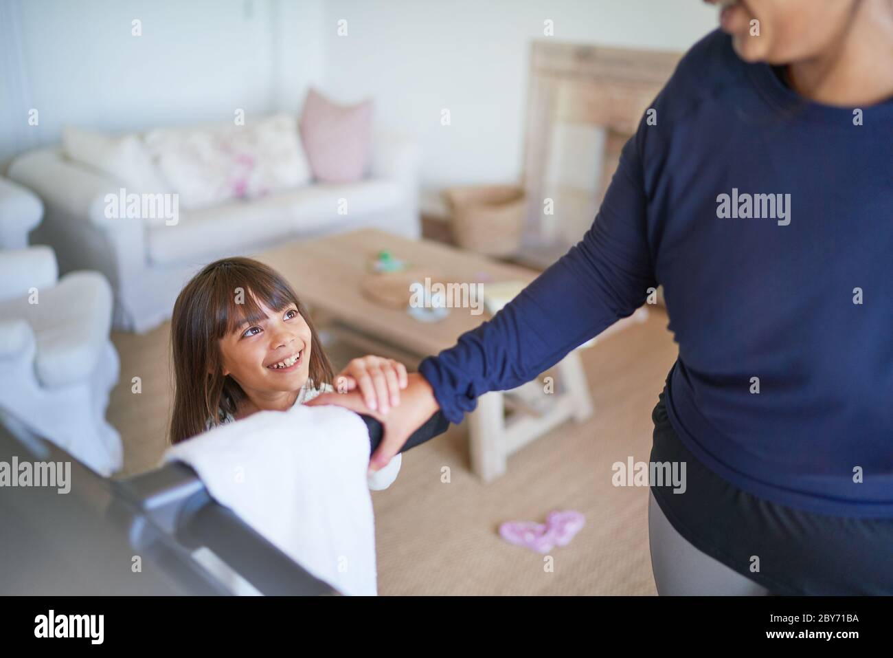 Figlia sorridente che guarda l'esercitazione della madre sulla pedana mobile Foto Stock