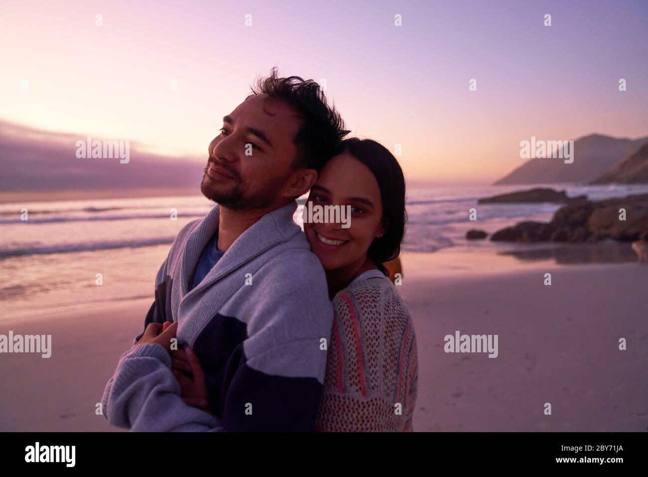 Ritratto felice affettuosa coppia abbracciata sulla spiaggia al tramonto Foto Stock