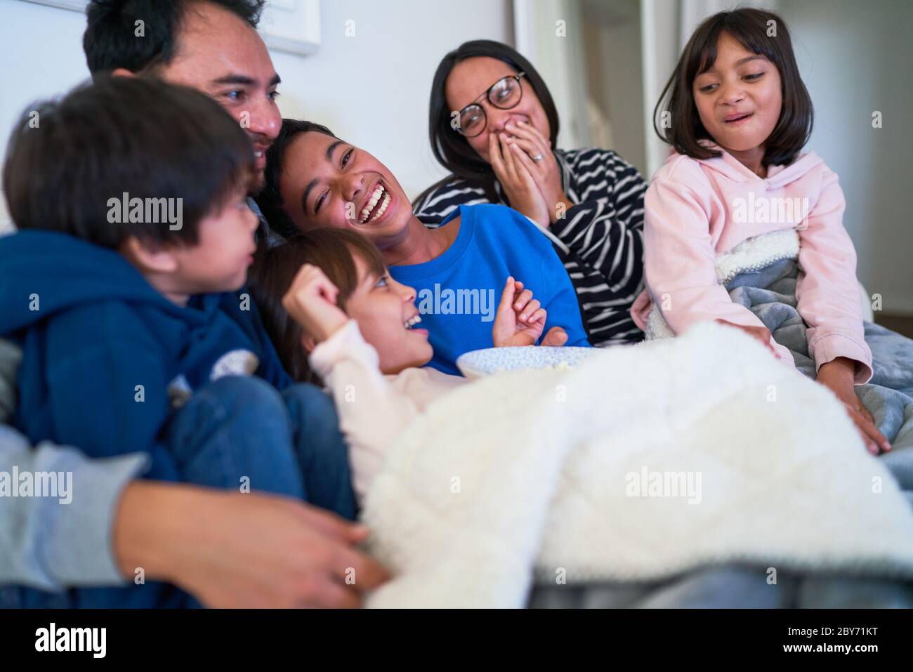 La famiglia ride felice sul divano Foto Stock