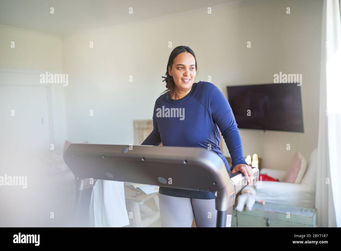Donna sorridente esercitando su tapis roulant Foto Stock