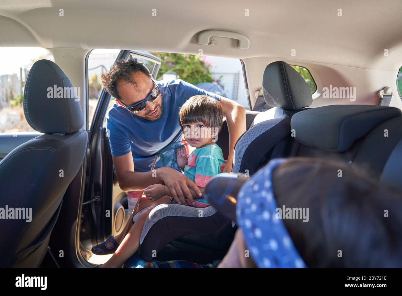 Padre che fissa il figlio del bambino nel seggiolino per auto Foto Stock