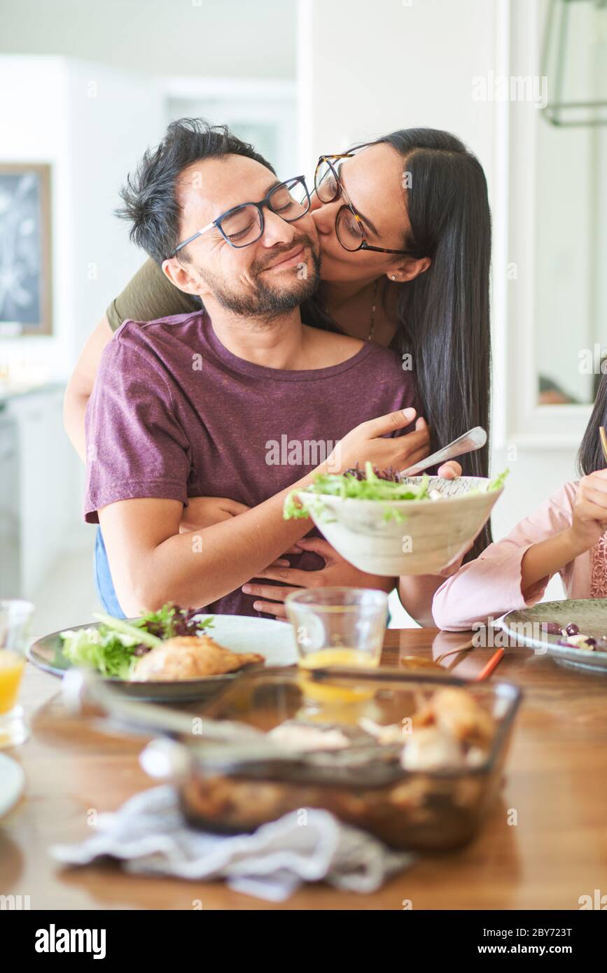 Affettuosa coppia baciando al tavolo da pranzo Foto Stock