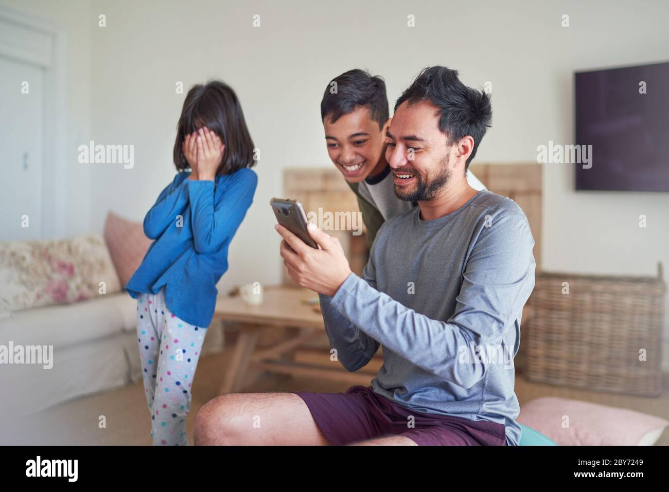 Padre e bambini che usano lo smartphone in soggiorno Foto Stock