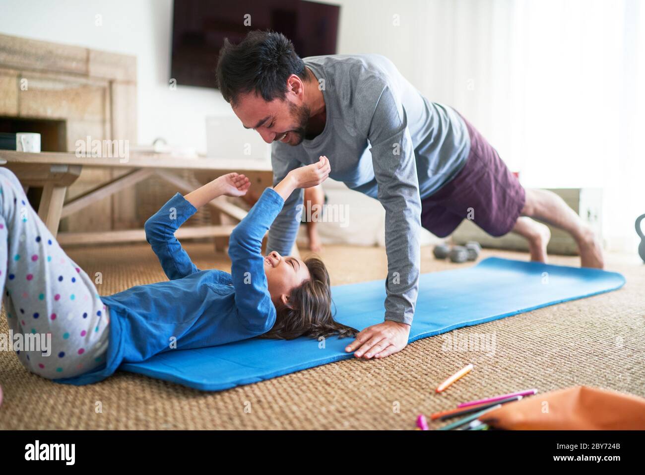 Il padre e la figlia giocosi che si esercitano in soggiorno Foto Stock