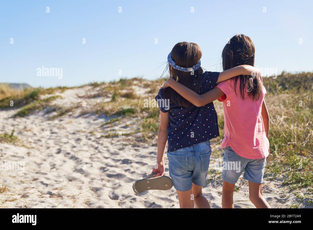Sorelle affettuose che camminano sulla soleggiata spiaggia Foto Stock