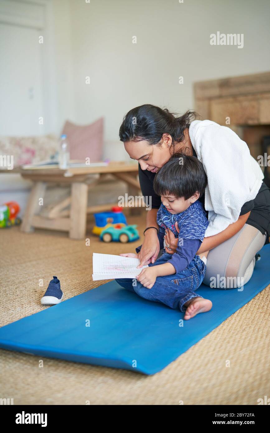 Figlio che mostra la madre che disegnano sul tappeto yoga Foto Stock