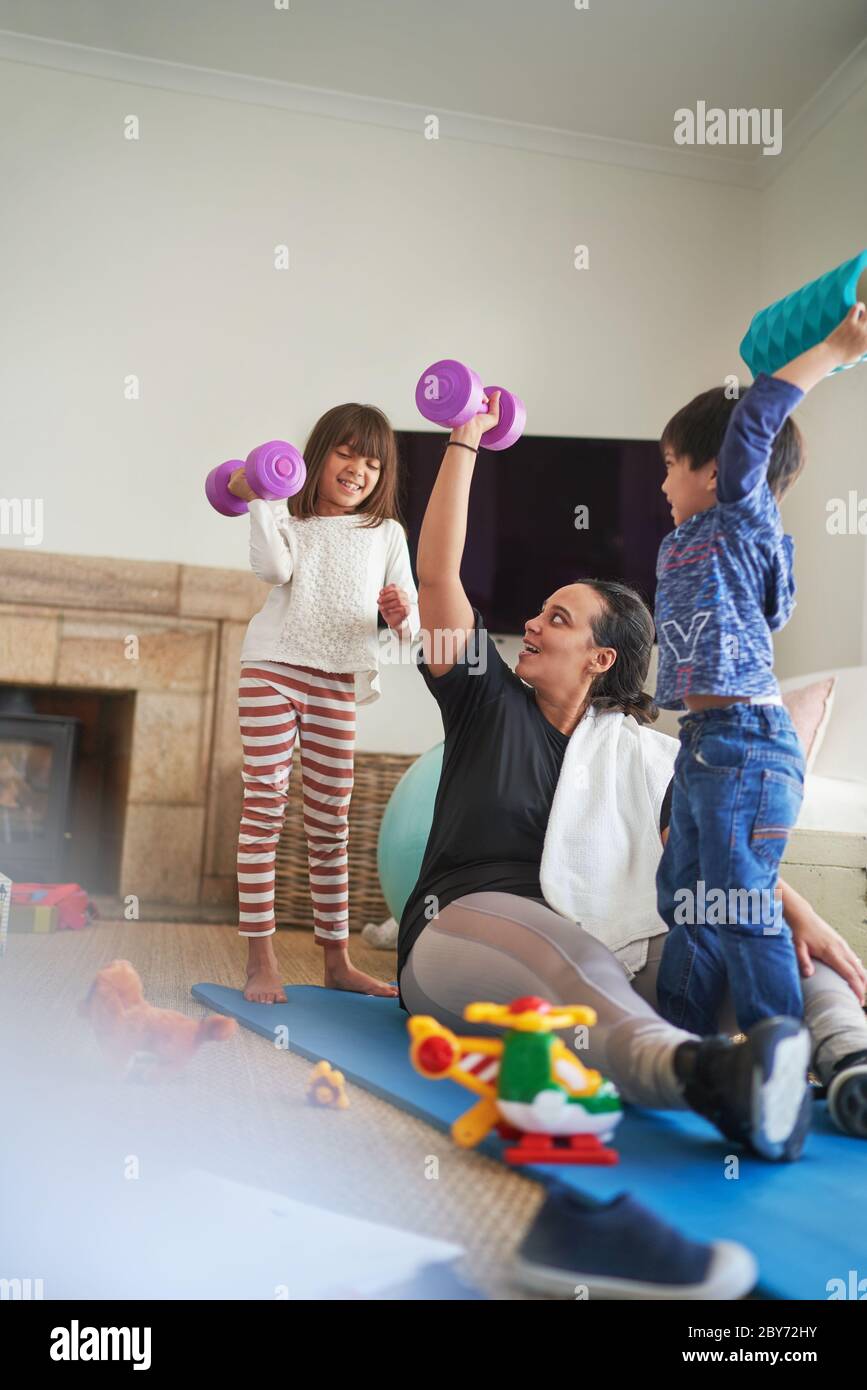 Madre e bambini che si allenano con i manubri in soggiorno Foto Stock