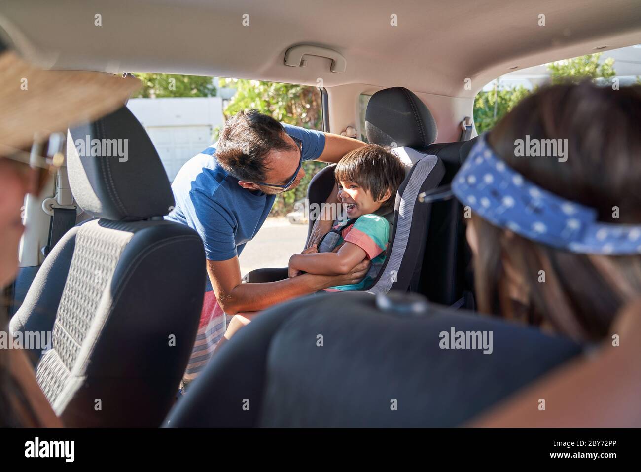 Padre che fissa il figlio nel sedile dell'auto Foto Stock