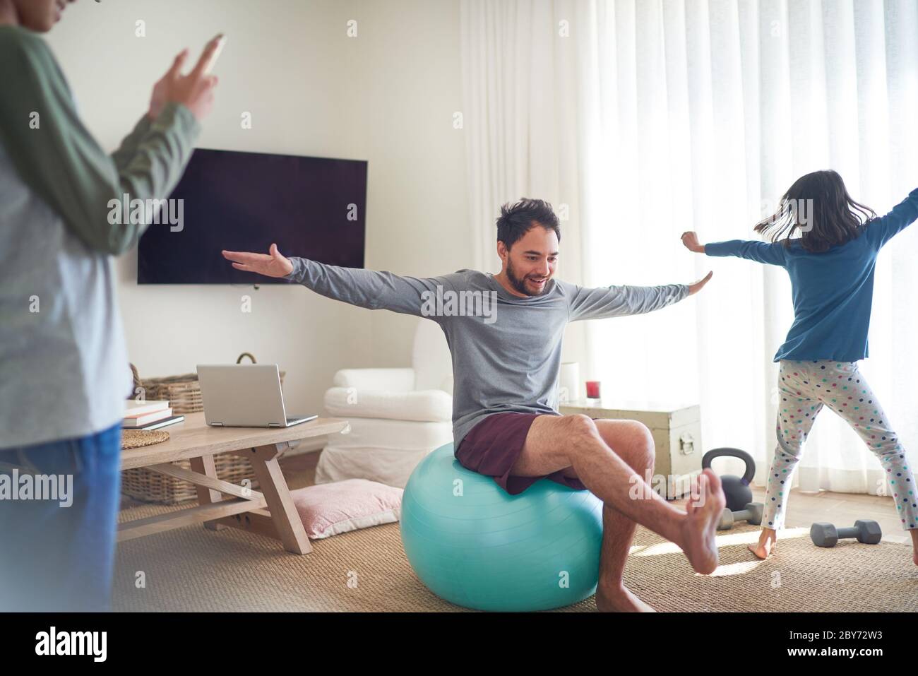 Padre e bambini che si esercitano e giocano in soggiorno Foto Stock