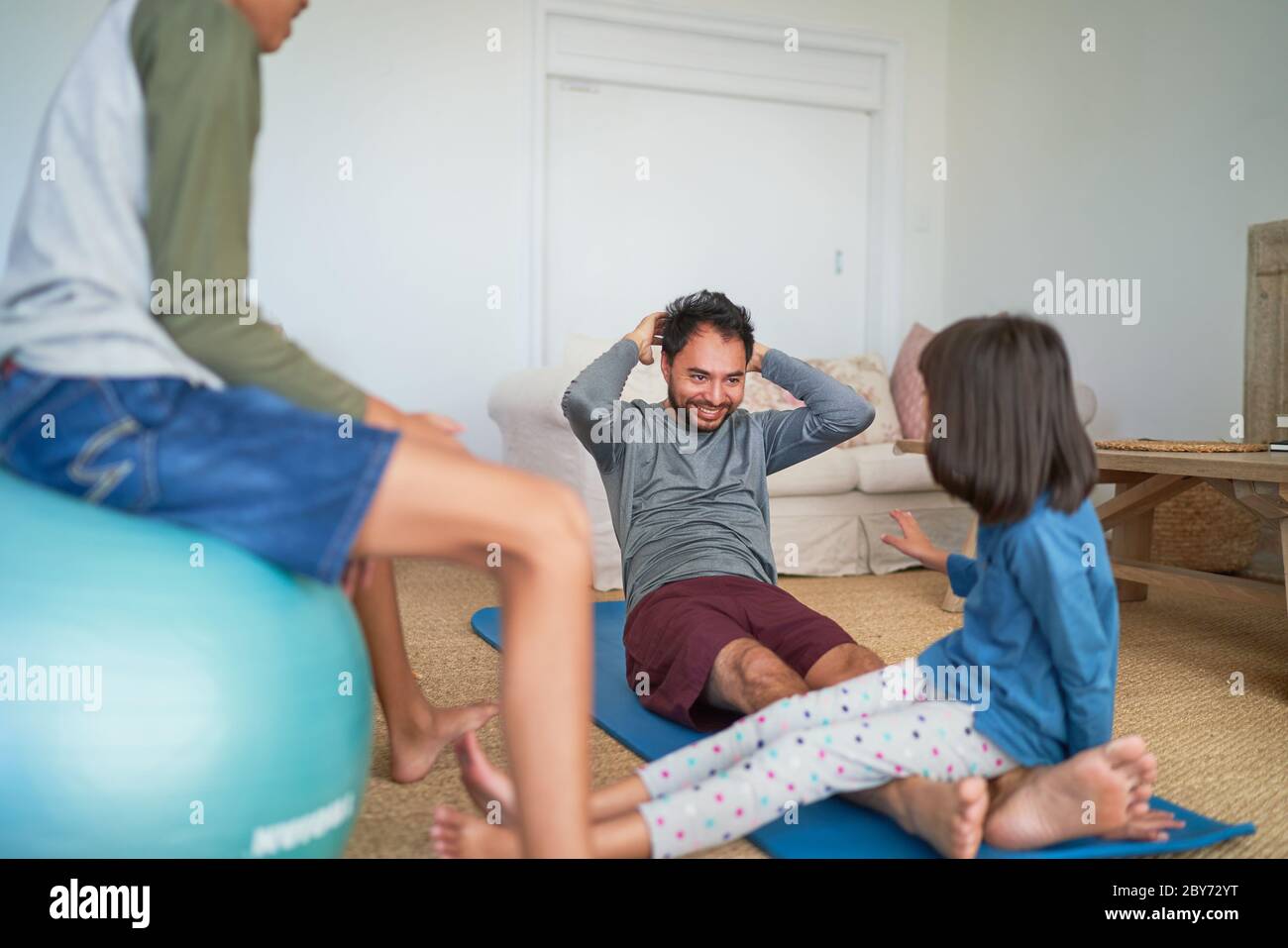 Padre e bambini che si esercitano in soggiorno Foto Stock