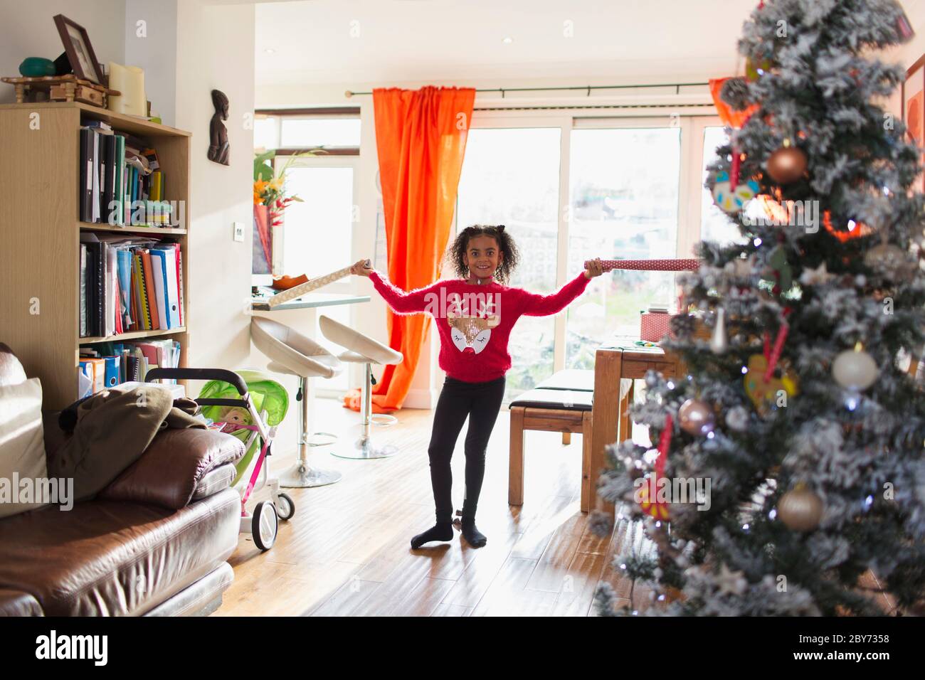 Ritratto ragazza felice in felpa di Natale che tiene la carta di imballaggio Foto Stock