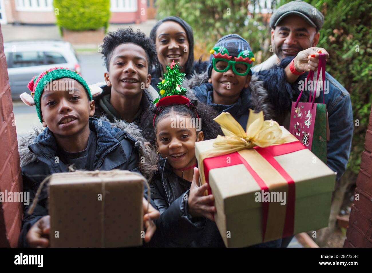 Ritratto felice famiglia arrivo con regali di Natale alla porta d'ingresso Foto Stock