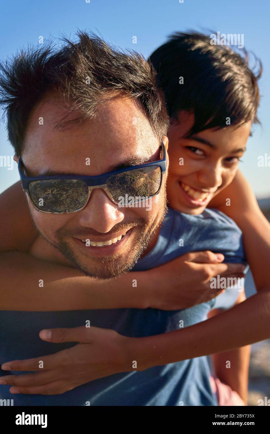 Ritratto felice padre piggybacking figlio Foto Stock