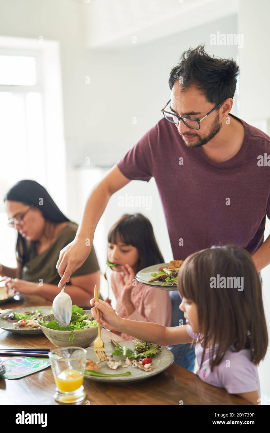 Famiglia che mangia pranzo insalata al tavolo Foto Stock