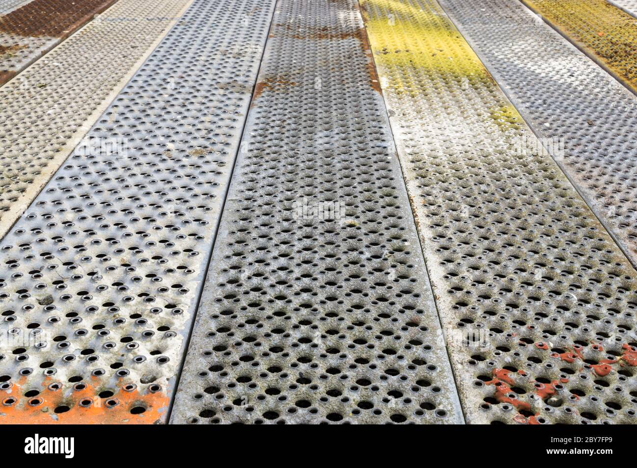 Fondo metallico con perforazione di fori quadrati. Struttura in acciaio grigio e colorato di lamiera di sabbia Foto Stock