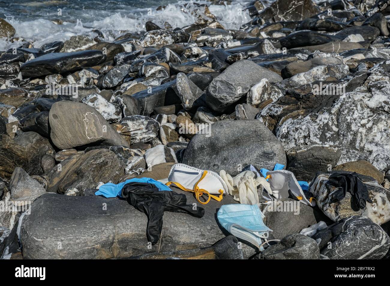 Rifiuti medici, maschera virus e guanti di plastica spazzatura scartata sulla costa rocciosa del mare, coronavirus covid19 inquinamento Foto Stock