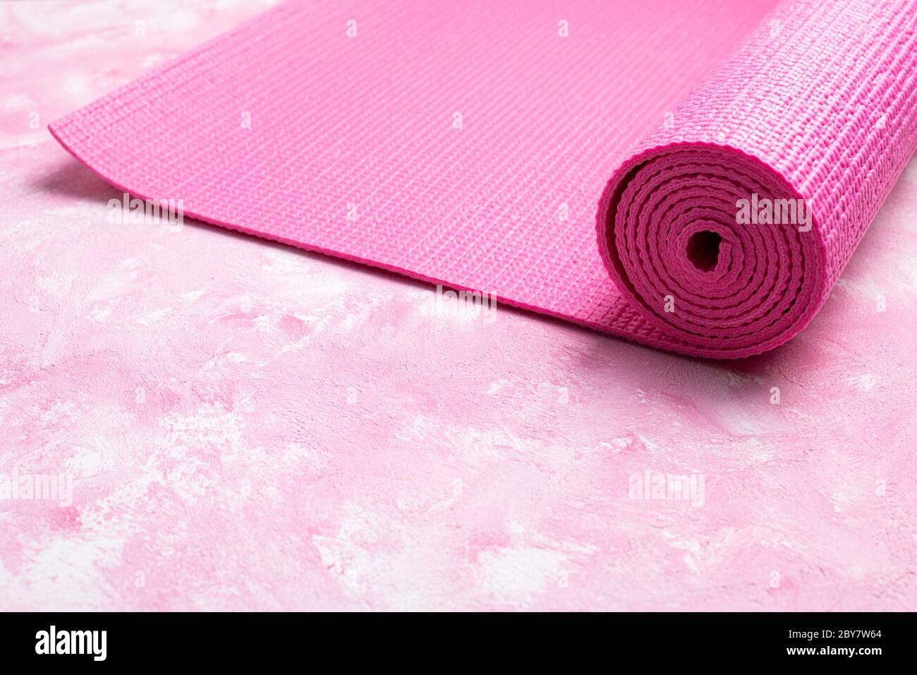 Tappetino yoga su sfondo rosa. Attrezzature per yoga. Concetto stile di vita sano, sport, meditazioni e relax. Vista dall'alto, spazio di copia Foto Stock