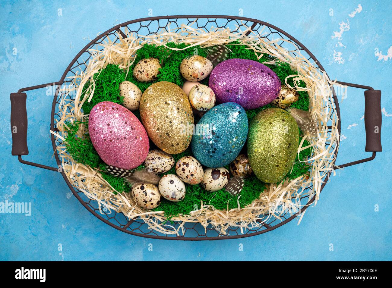 Composizione pasquale con uova di Pasqua colorate sul muschio in cestino. Biglietto di auguri di Pasqua per le vacanze di primavera. Vista dall'alto Foto Stock
