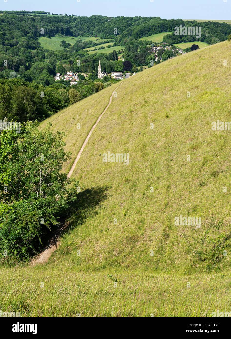 Rodborough comune sopra Stroud nelle colline Cotswold del Gloucestershire UK con ripide pendenze ricche di specie praterie con la chiesa di Woodchester oltre Foto Stock