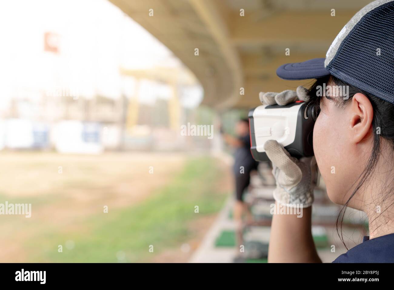 Le mani femminili indossano guanti professionali con moderno rilevatore ottico di gamma bianco e nero e guardano al rilevatore ottico di gamma utilizzato per il golf o. Foto Stock