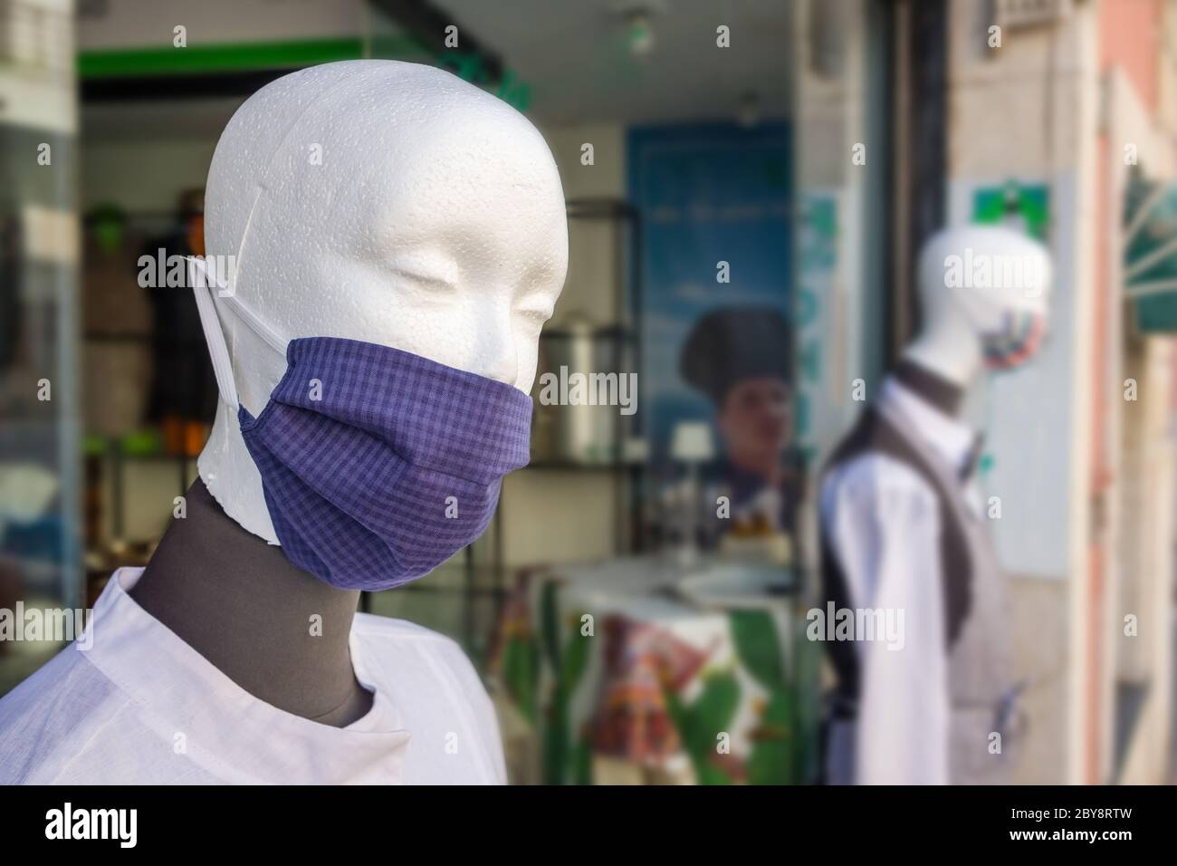 Manichini in vetrina di negozio che indossa maschere contro il coronavirus durante la pandemia Covid-19 Foto Stock