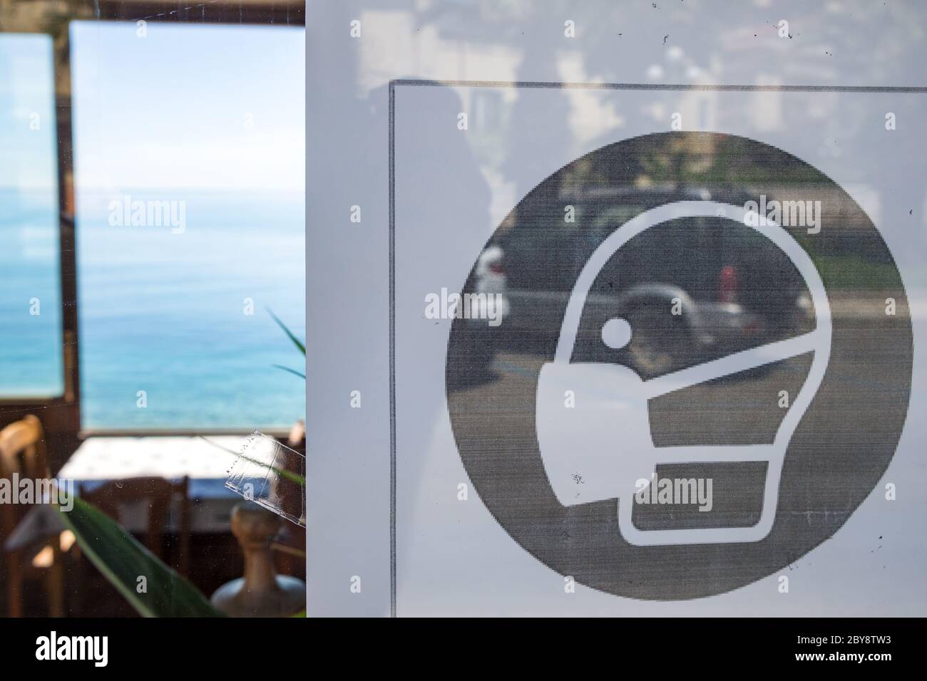 Cartello di quarantena 'e' obbligatorio indossare una maschera all'interno' sulla porta del ristorante in Sicilia, Italia Foto Stock
