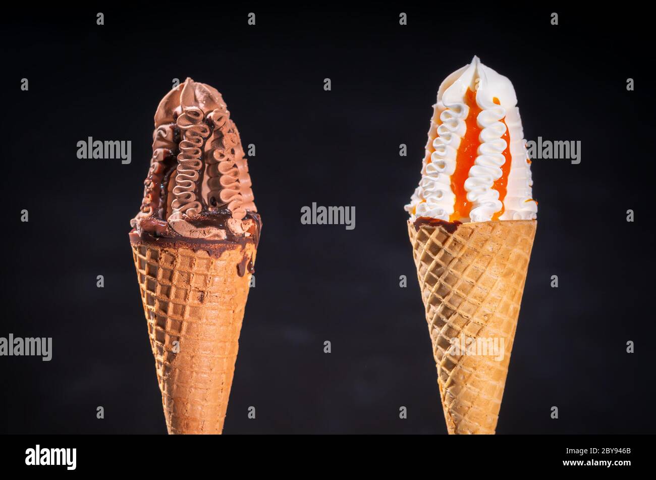 Due Gusti Di Gelato Surgelato In Coni O Cornetti Di Zucchero Con Cioccolato Condito Con Salsa E Vaniglia Con Gocce Di Frutta Su Nero Foto Stock Alamy