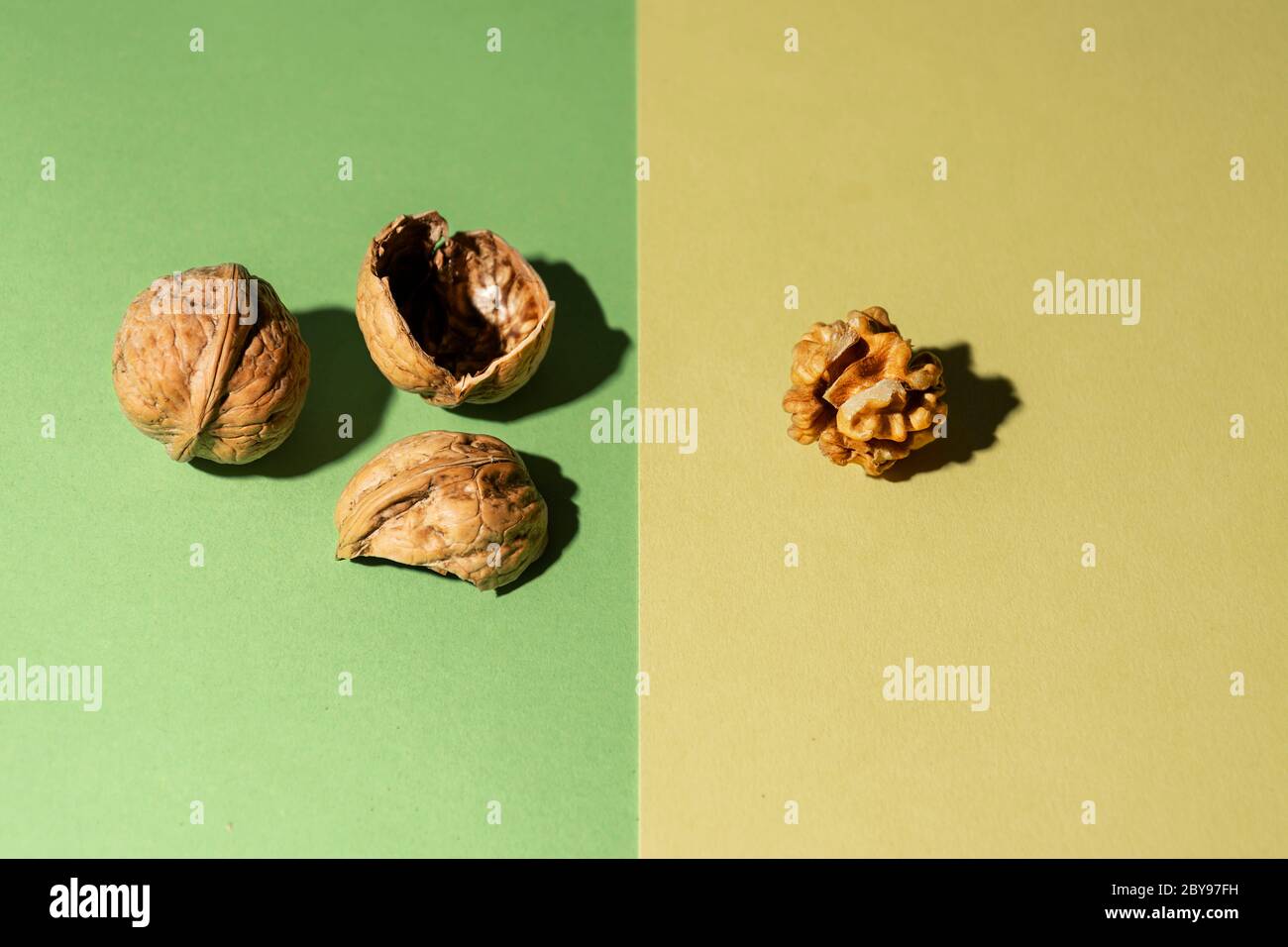 Dado pelato con i suoi gusci e un altro dado in guscio su sfondo verde e giallo Foto Stock