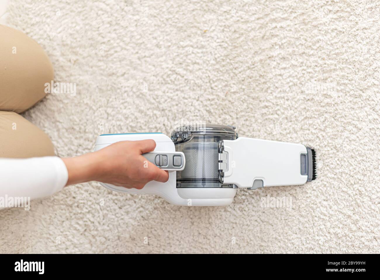 Donna che aspira mobili in una casa con un aspirapolvere portatile  portatile portatile Foto stock - Alamy