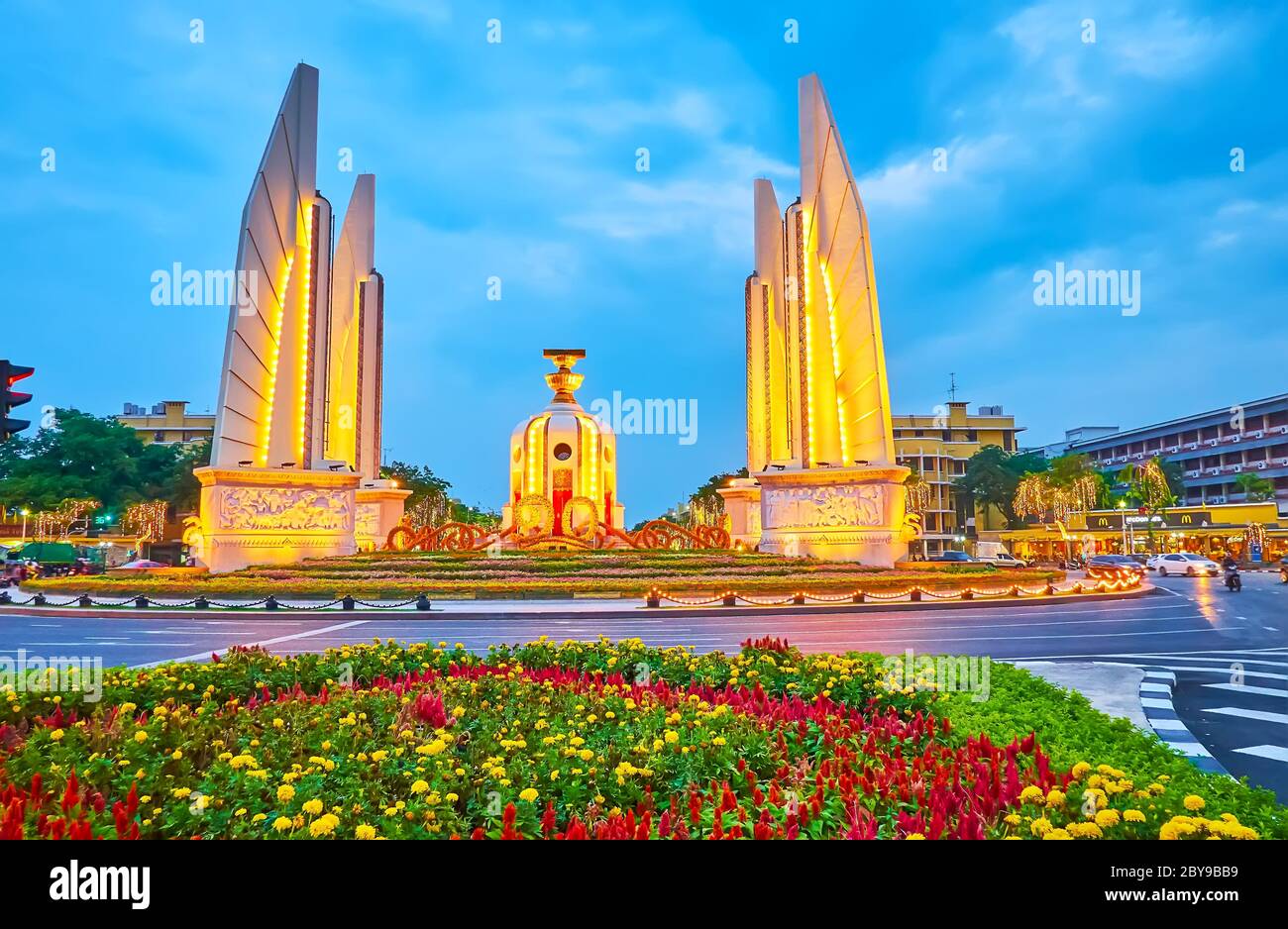 BANGKOK, THAILANDIA - 13 MAGGIO 2019: Il cielo crepuscolo sopra il Monumento illuminato della democrazia, circondato da aiuole colorate, il 13 maggio a Bangkok Foto Stock