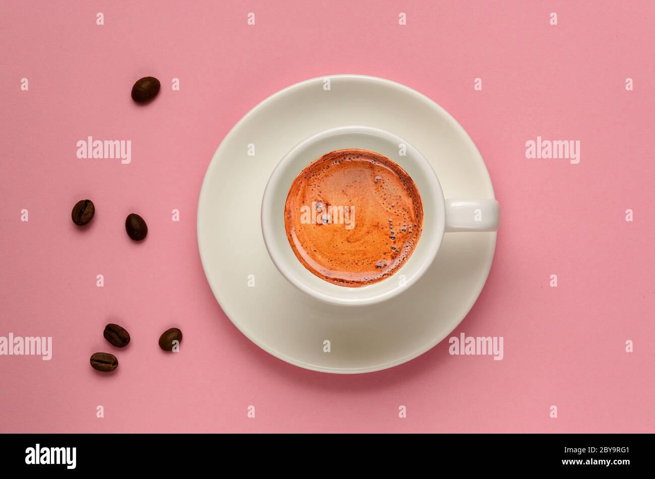 Creativa disposizione piatta di tazza di caffè bianca e alcuni chicchi di caffè su sfondo rosa millenario. Stile minimalista. Ma il caffè è il primo concetto. Spazio di copia Foto Stock