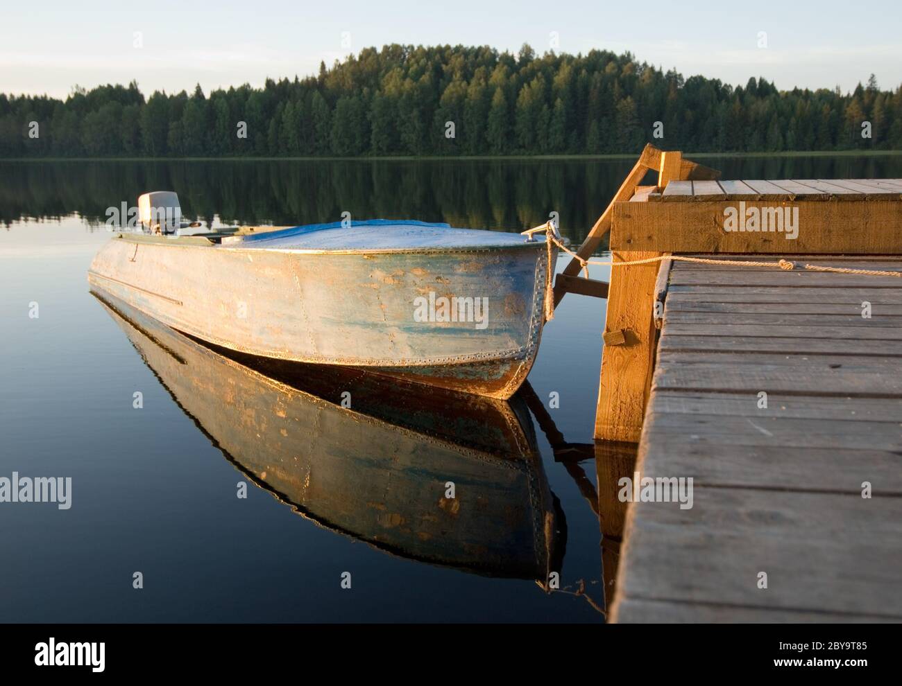 barca che si riflette in acque calme del lago forestale Foto Stock