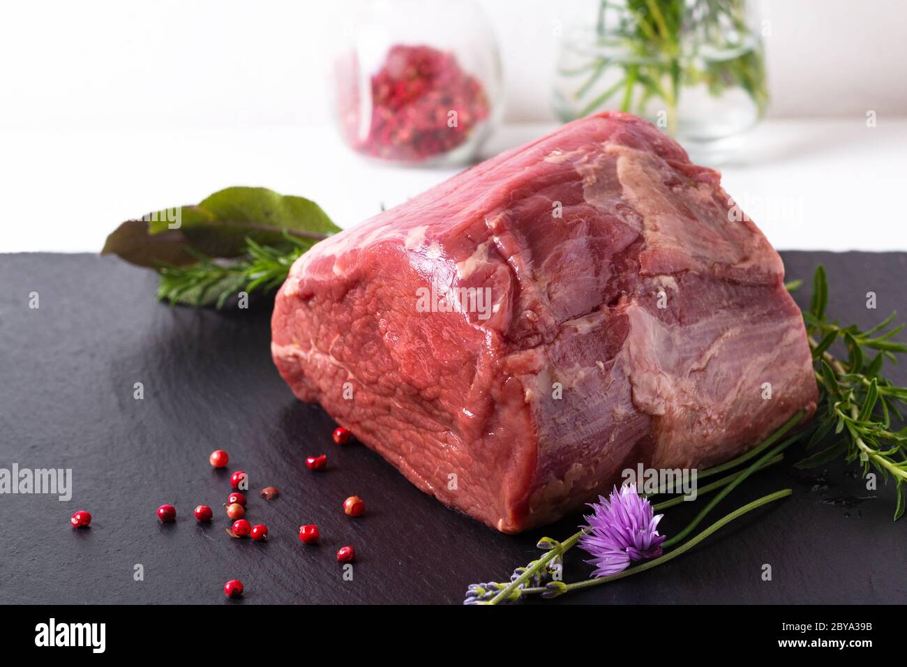 Concetto alimentare biologico intero pezzo di carne di manzo rotonda cruda su piastra di pietra ardesia nera con spazio di copia Foto Stock