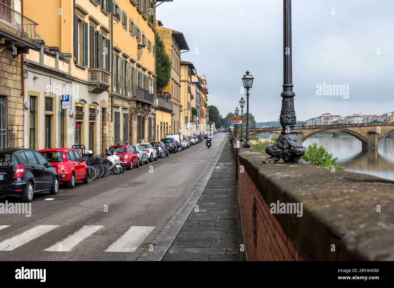 Riverside Street - una vista nuvolosa di ottobre mattina di una stretta strada a senso unico, lungo il lato del fiume Arno, nel centro storico di Firenze. Toscana, Italia. Foto Stock