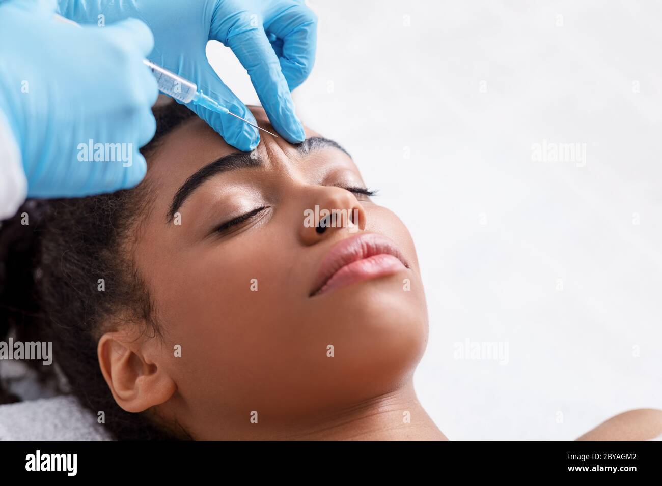 Giovane donna nera che riceve iniezione di botox al salone di bellezza Foto Stock