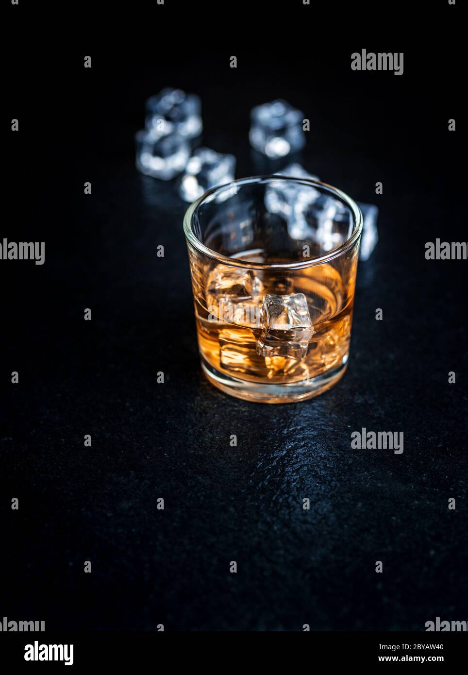 Whisky, whisky, borbonio o cognac con cubetti di ghiaccio su tavola di pietra nera Foto Stock