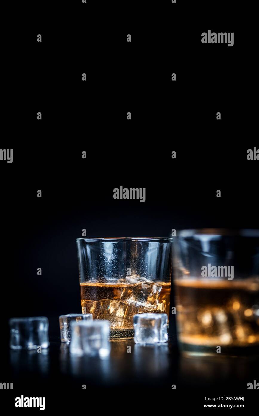 Whisky, whisky, borbonio o cognac con cubetti di ghiaccio su tavola di pietra nera Foto Stock