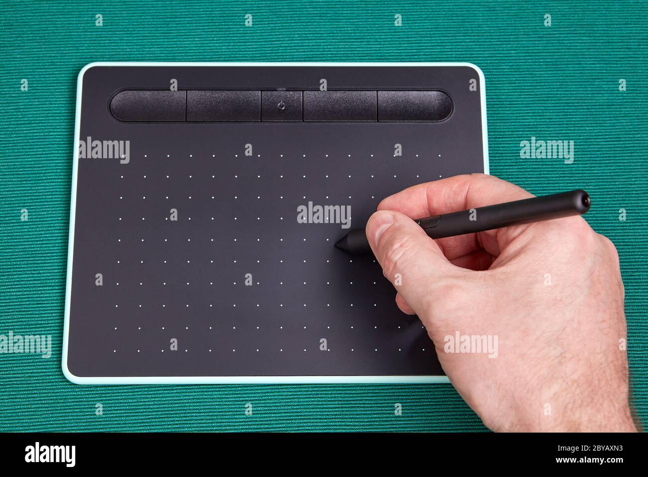 La mano dell'artista tiene uno stilo o una penna sullo schermo di un tablet grafico, si tratta di un dispositivo di input quando si utilizzano programmi di elaborazione delle immagini. Fotografia Foto Stock