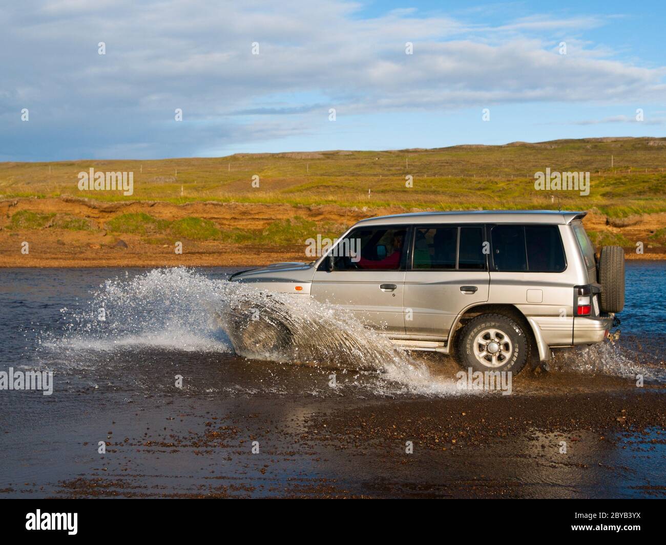 Auto offroad che si affaccia sul fiume e spruzzi d'acqua, vista laterale Foto Stock