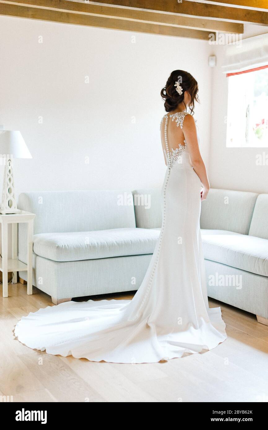 Sposa che guarda fuori dalla finestra e si è abbronzato fuori abito da sposa Foto Stock