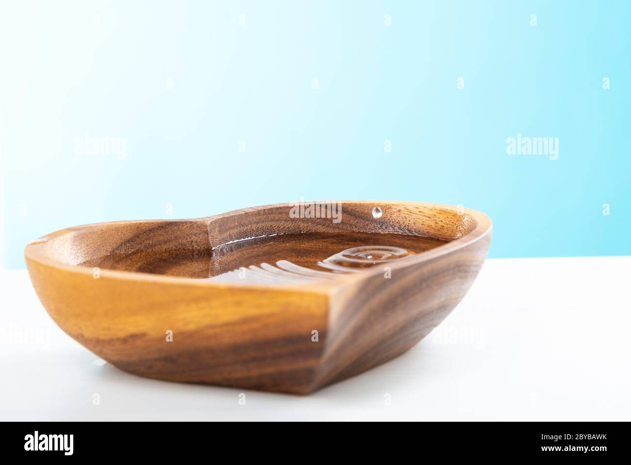 Una goccia d'acqua cadde in una piastra di legno a forma di cuore. Concetto di giornata dell'acqua. Proteggere l'acqua potabile. Esaurimento dell'acqua potabile sulla Terra Foto Stock