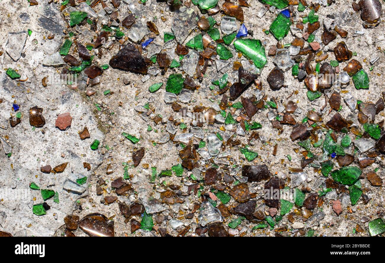 Vetri colorati rotti su fondo di cemento, molti piccoli pezzi Foto Stock