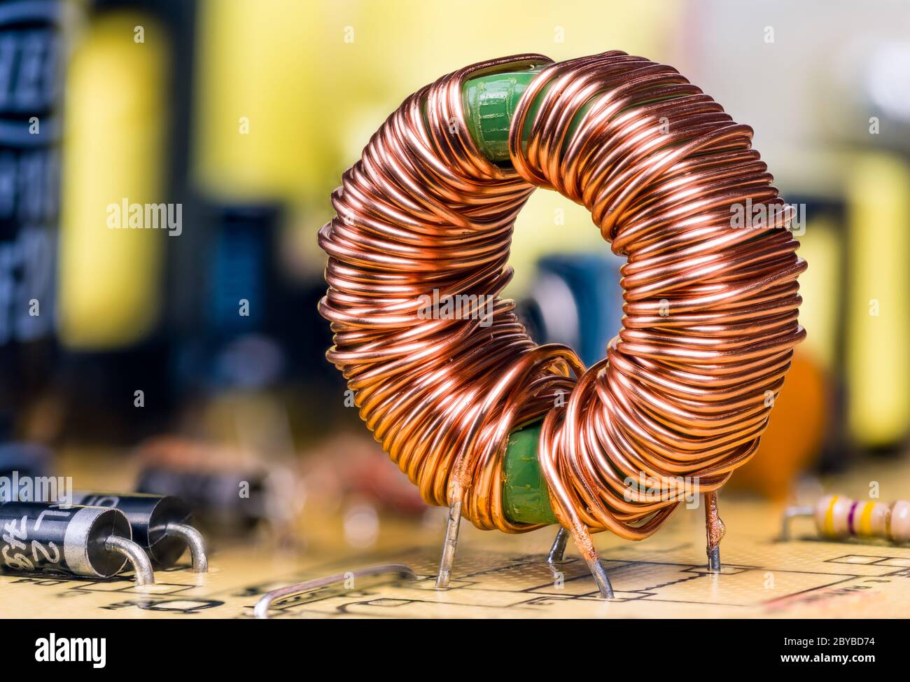 Bobina a induzione con avvolgimento del filo di rame saldato sulla scheda a circuito stampato. Induttore toroidale con nucleo in ferrite magnetica. Informazioni sui componenti elettronici. Foto Stock