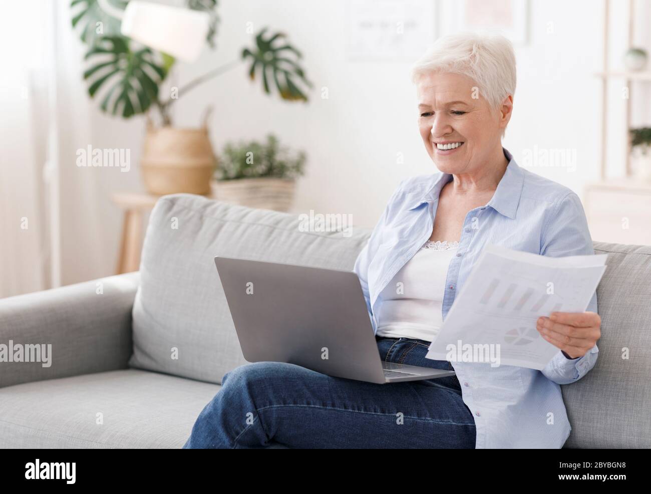 Azienda per i pensionati. Donna anziana che lavora con il laptop e documenti a casa Foto Stock